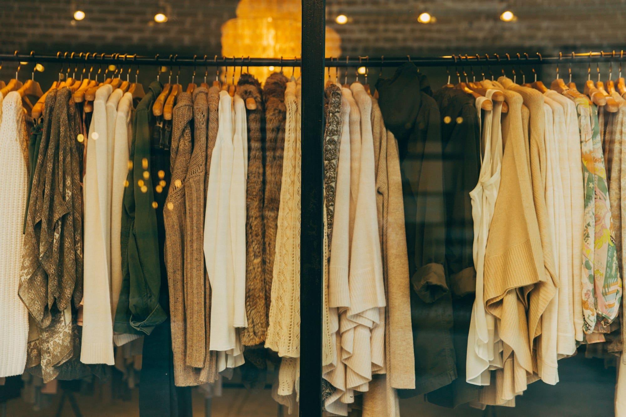 Neutral-toned garments hanging on a boutique rail under warm light