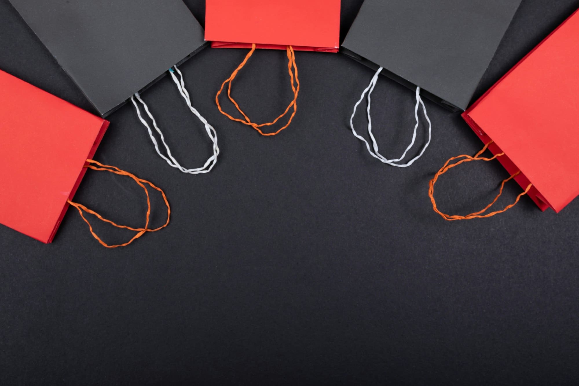 Black and red boutique shopping bags arranged on a dark surface