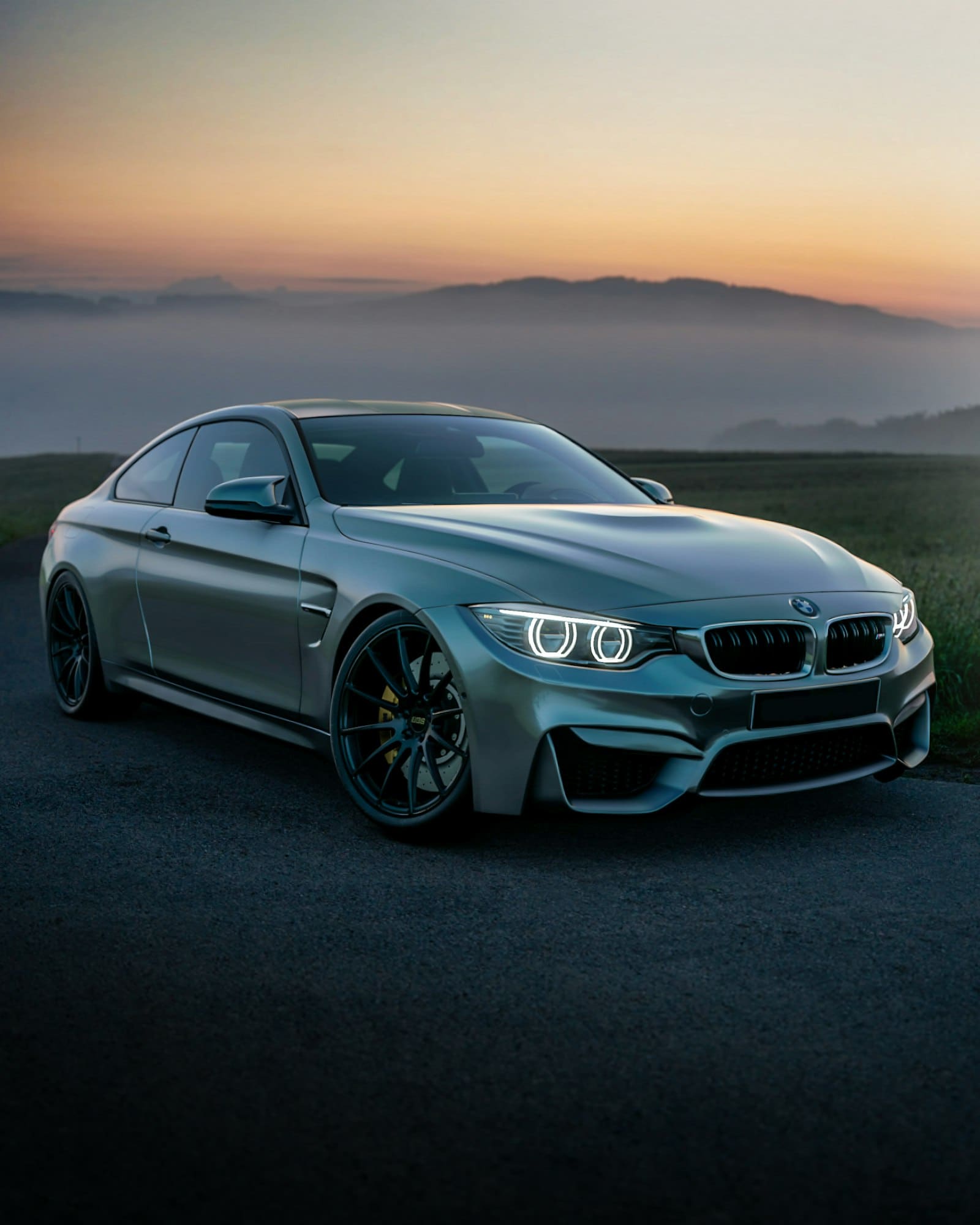 A grey grand tourer parked against a hazy sunset sky