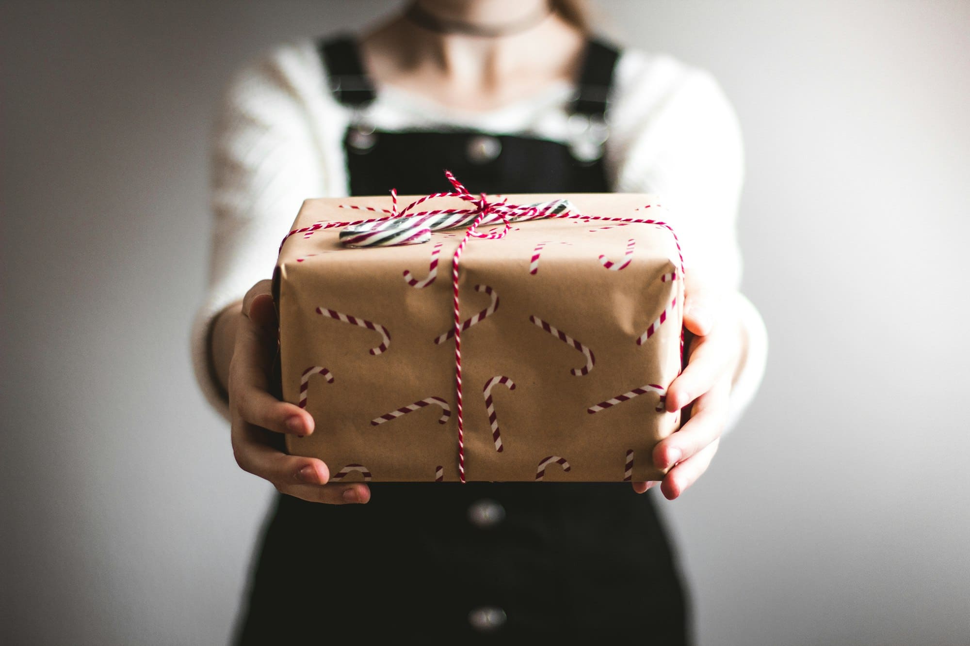 Hands presenting a carefully wrapped parcel tied with string